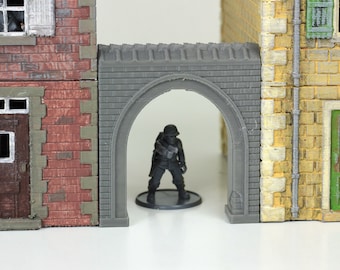 May include: A gray brick archway with a textured surface. The archway is part of a model building set. A miniature figure of a soldier is standing in the archway.