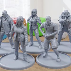 May include: Six grey painted miniature figures of people standing on round bases. The figures are posed in different stances and are wearing various clothing. The figures are on a wooden surface.