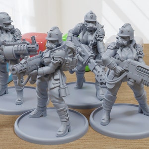 May include: Four gray plastic miniature figures of female soldiers wearing gas masks and helmets, holding futuristic weapons. The figures are standing on round bases.