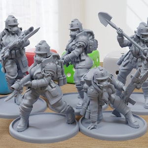 May include: Five grey plastic figurines of people wearing gas masks and helmets. The figurines are holding various weapons and tools, including a shovel, a rifle and a knife. The figurines are standing on round bases.