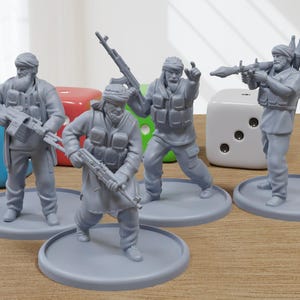 Può includere: Quattro figurine di plastica grigia di soldati che indossano copricapi e portano armi. Le figurine sono in piedi su basi circolari grigie. Le figurine sono su una superficie di legno.