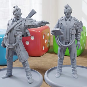 May include: Two gray painted miniature figures of men wearing glasses and suits. One figure is holding a gun and the other is holding a small book. The figures are standing on gray bases.