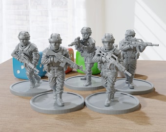 以下が含まれることがあります： グレーのミニチュア兵士のフィギュアのコレクション。それぞれがライフルを装備し、円形の台座に立っています。フィギュアは木製の表面に配置され、背景にはいくつかのサイコロがあります。