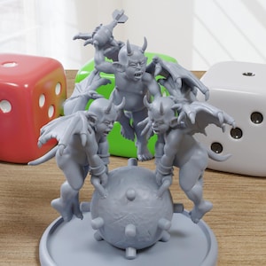 May include: A gray figurine of several winged demons surrounding a spiked ball, with large dice in blue, red, green, and white in the background. The dice have white dots.