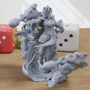 May include: A gray figurine of a warrior woman with ornate armor and a crown, standing on a cloud-like base. Colorful dice in blue, red, green, and white are in the background. The figurine is approximately 6 inches tall.
