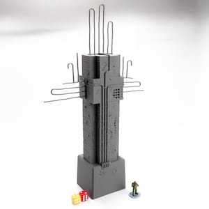 May include: A gray, industrial-style model of a tower with protruding metal rods and wires. The model has a rectangular base and is accompanied by a miniature figure and two dice. The tower is approximately 10 inches tall.