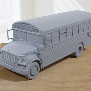 May include: A gray toy school bus with the words "SCHOOL BUS" printed on the front. The bus has a yellow stop sign on the side.