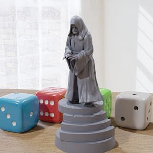 Peut inclure: Une figurine grise d'une figure vêtue d'une robe debout sur une plateforme grise à quatre marches. La figurine est entourée de quatre dés, un bleu, un rouge, un vert et un gris.