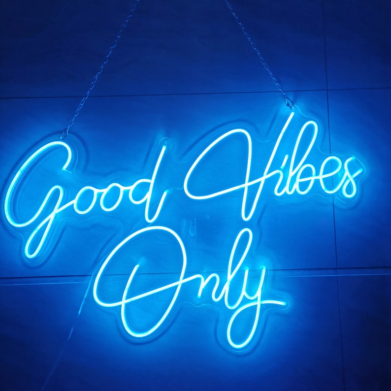 May include: Blue neon sign with the text "Good Vibes Only" hanging on a blue wall.