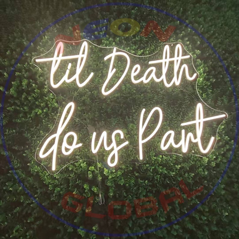 Op de afbeelding: Een wit neonbord met de tekst "til death do us part" in een cursief schrift. Het bord is verlicht en hangt aan een groene muur.