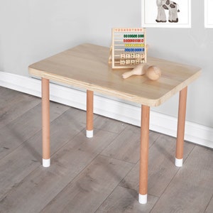 Handcrafted wooden kids table and chair set in natural finish, perfect for play and study. The table features a rectangular top with rounded corners, accompanied by two matching chairs with comfortable, ergonomic seats.