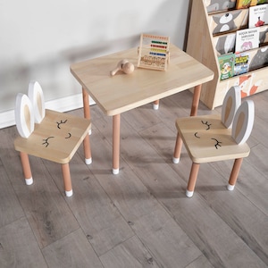 Handcrafted wooden kids table and chair set in natural finish, perfect for play and study. The table features a rectangular top with rounded corners, accompanied by two matching chairs with comfortable, ergonomic seats.