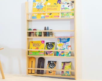 May include: A wooden bookshelf with five shelves, each holding colorful children's books. The books have titles in Turkish, including "Sebzeler ve Meyveler" and "Cizgilerle Sekilleri".