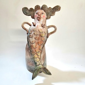 Saucy Sea Siren, a handmade ceramic mermaid sitting a top a rock singing for sailors.