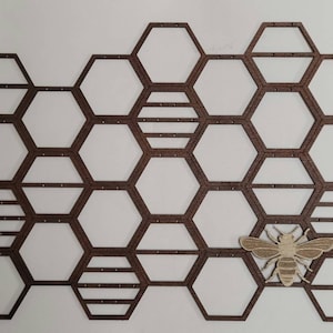 Puede incluir: Un soporte para pendientes de madera en forma de panal con un peque&ntilde;o recorte de abeja de madera. El soporte tiene 18 compartimentos hexagonales para pendientes.