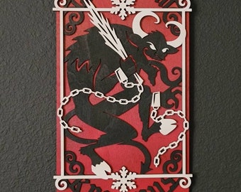 May include: A red wooden sign with a white silhouette of a horned creature with chains and a snowflake. The sign reads "Gruss vom Krampus".