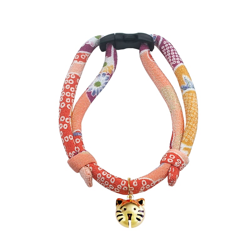 May include: A red, orange, and purple patterned cat harness with a gold cat-shaped bell charm.