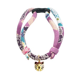May include: A purple and pink patterned cat collar with a gold cat-shaped bell charm.