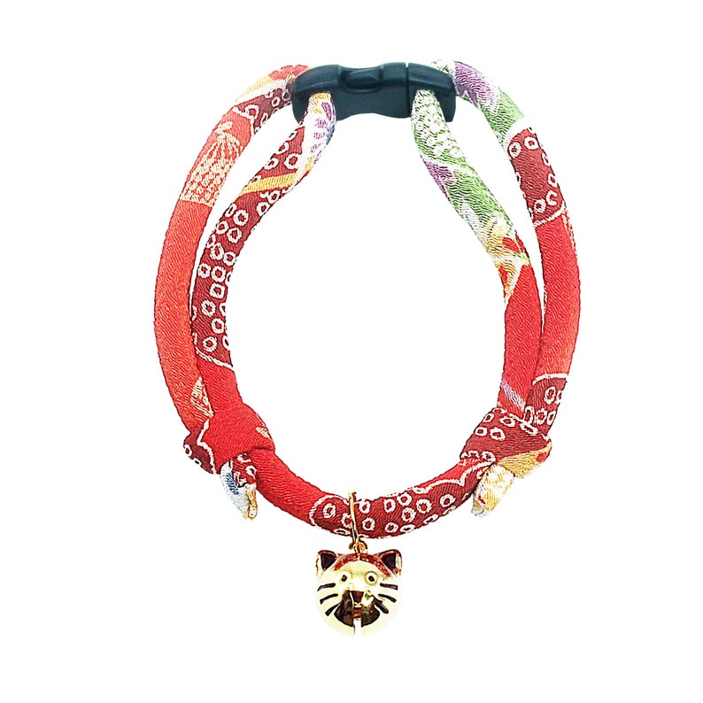 May include: Red and gold cat collar with a cat-shaped bell charm. The collar is made of fabric with a traditional Japanese pattern.