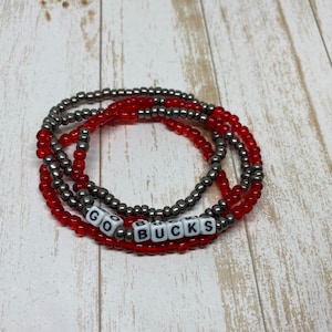 May include: Red and silver beaded bracelet with the words "GO BUCKS" spelled out in white letters on red beads.