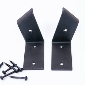 May include: Two black metal shelf brackets with three screw holes each, and a pile of black screws.