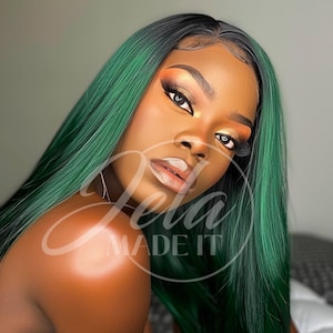 May include: A woman with long, green and black ombre hair. The hair is styled in long layers. The woman is wearing makeup with gold and orange eyeshadow. The text "Zela MADE IT" is overlaid on the image.