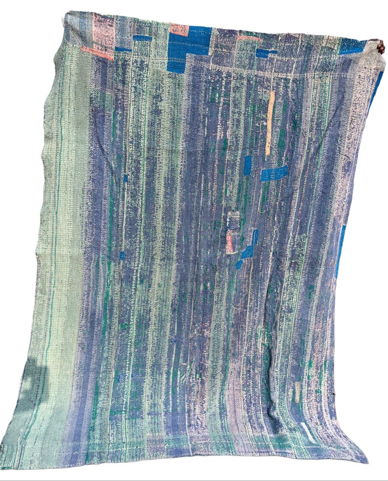May include: A blue, green, and white patterned textile with vertical stripes and patches of color. The fabric appears to be a quilt or blanket, with a textured, worn appearance. The color palette includes shades of blue, green, and pink.