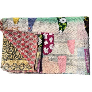 May include: A multi-coloured patchwork clutch bag with a variety of patterns and textures. The design includes sections of pink, white, yellow, and green fabric, stitched together. The clutch is folded over, showing the interior lining.