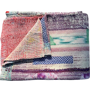 Könnte beinhalten: Gefaltete Patchwork-Decke mit einer Vielzahl von Farben und Mustern. Die Decke hat rote, violette, blaue und grüne Abschnitte mit sichtbaren Nähten. Das Design umfasst Streifen, geometrische Formen und florale Elemente. Ein gemütliches, handgefertigtes Textil.