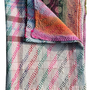 May include: A colorful, handmade quilt with a patchwork design. The quilt features a variety of colors, including pink, orange, green, and blue. The quilt is made of a soft, textured fabric and is likely used as a bed covering or decorative throw.