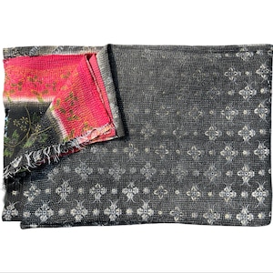 May include: A reversible textile with a dark gray patterned design on one side and a vibrant pink and floral pattern on the other. The edges are frayed, adding a rustic touch. This textile is suitable for use as a blanket or throw.