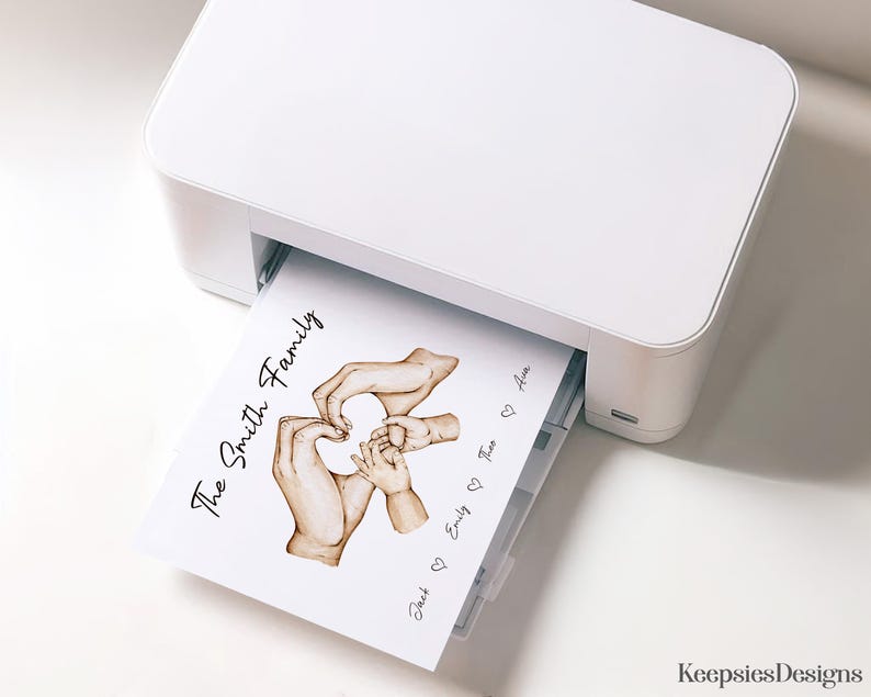May include: A white printer outputting a sheet of paper featuring a watercolor illustration of adult and child hands forming a heart shape. The text reads The Smith Family, with the names Jack, Emily, Theo, and Ava separated by heart icons.