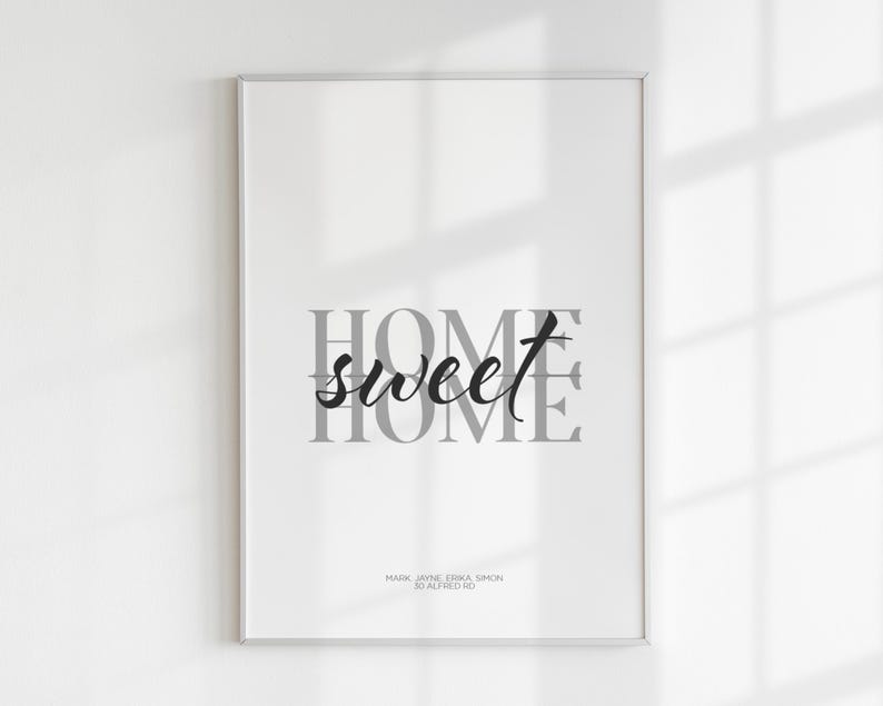 A close-up of a framed home sweet home print with soft window light and shadows across it.