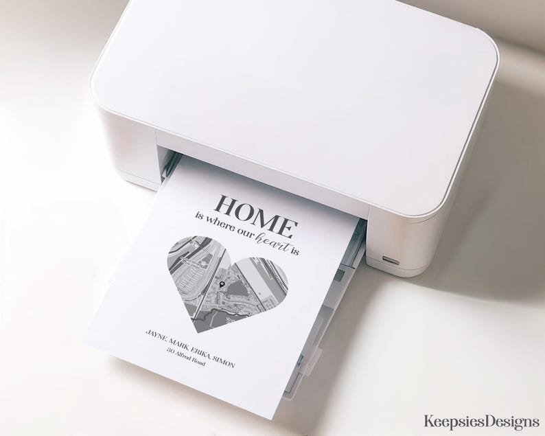 Pode incluir: Uma impressora branca imprimindo um design em preto e branco com o texto "HOME is where our heart is". O design inclui um mapa em forma de cora&ccedil;&atilde;o e os nomes Jayne, Mark, Erika e Simon.
