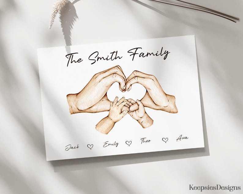 May include: A white rectangular print featuring a brown ink illustration of two adult hands and two infant hands forming a heart shape. The text The Smith Family appears at the top, with the names Jack, Emily, Theo, and Ava separated by hearts below.