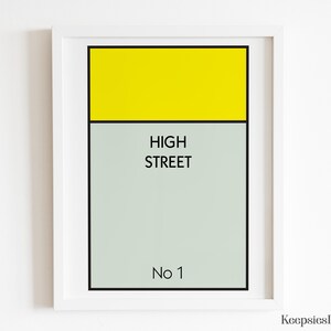 May include: A framed wall art print featuring a rectangular graphic design with a bright yellow top section and a light grey bottom section. The text HIGH STREET is printed in black in the centre, with No 1 printed in black at the bottom.