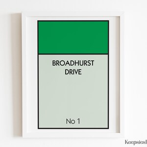 May include: A framed rectangular print featuring a green horizontal bar at the top, followed by the text BROADHURST DRIVE in black capital letters, and the text No 1 at the bottom, all set against a light grey background with a black border.