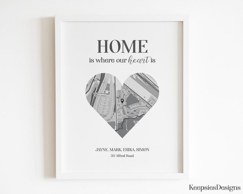 Pode incluir: Uma impress&atilde;o emoldurada com o texto "HOME is where our heart is". Um mapa em forma de cora&ccedil;&atilde;o est&aacute; no centro. Abaixo do cora&ccedil;&atilde;o est&atilde;o nomes e um endere&ccedil;o. A impress&atilde;o est&aacute; em uma moldura branca.