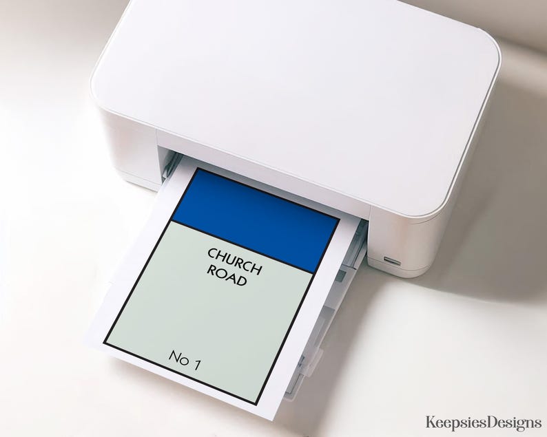 May include: A white desktop printer outputting a rectangular sheet of paper featuring a blue header bar above a light grey field with the black text CHURCH ROAD and the text No 1 at the bottom, all enclosed within a thick black border frame.
