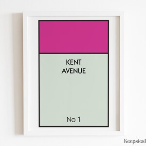 May include: A framed rectangular wall art print featuring a magenta horizontal bar at the top, a light grey background, and black text that reads KENT AVENUE and No 1. The design is enclosed in a simple white frame with a thin black border.