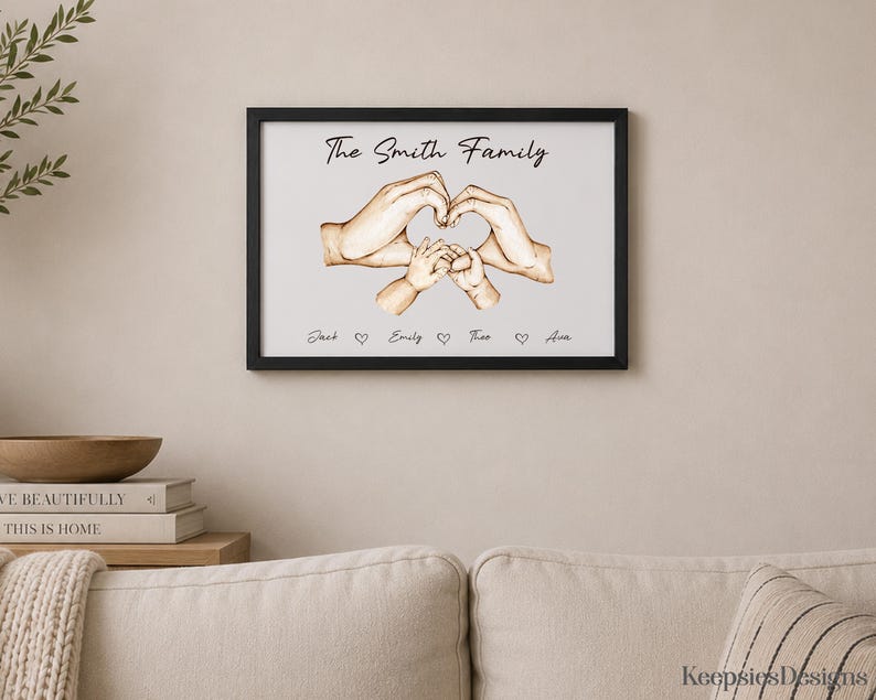 May include: A framed wall print featuring the text The Smith Family above an illustration of four hands forming a heart shape. Below the hands, the names Jack, Emily, Theo, and Ava are printed in black script, separated by small heart icons.