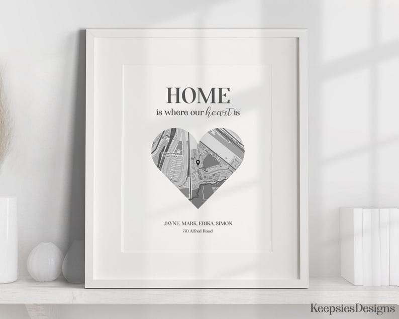 Pode incluir: Impress&atilde;o emoldurada em preto e branco com o texto "HOME is where our heart is". Um mapa em forma de cora&ccedil;&atilde;o est&aacute; centralizado abaixo do texto. Os nomes Jayne, Mark, Erika e Simon est&atilde;o listados abaixo do mapa, juntamente com um endere&ccedil;o.