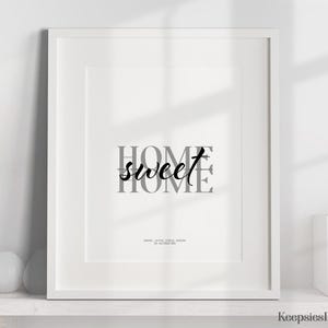 A framed home sweet home print displayed on a white shelf alongside decorative objects.