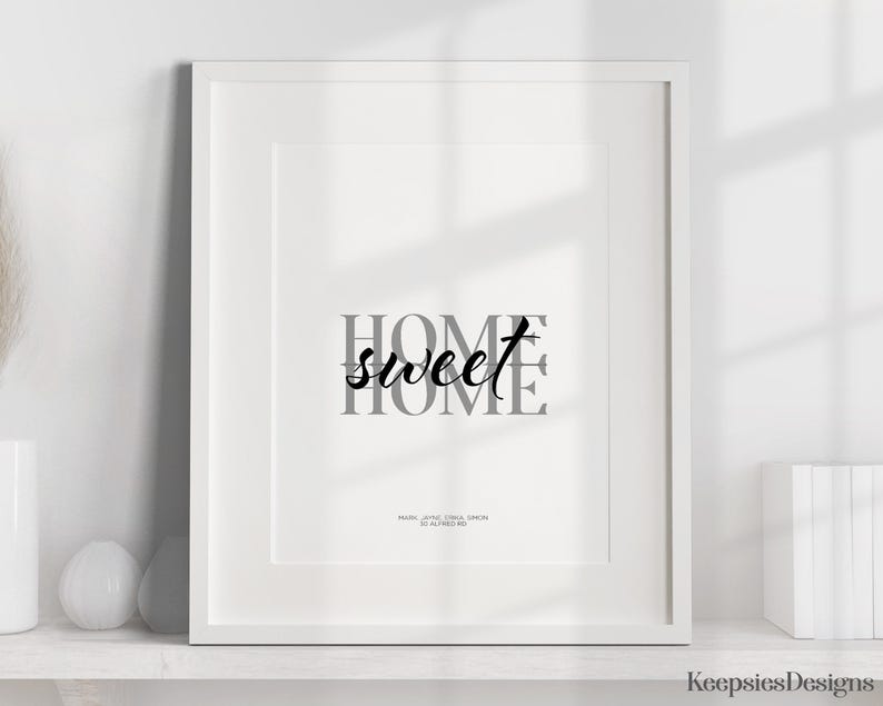A framed home sweet home print displayed on a white shelf alongside decorative objects.