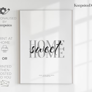 A framed home sweet home print in a thin white frame leaning against a wall with window shadows.