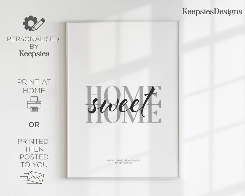 A framed home sweet home print in a thin white frame leaning against a wall with window shadows.