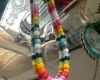 Op de afbeelding: Een kleurrijke kralenketting met afwisselend turquoise, wit, groen, geel, oranje, rood, roze en lichtblauwe kralen.