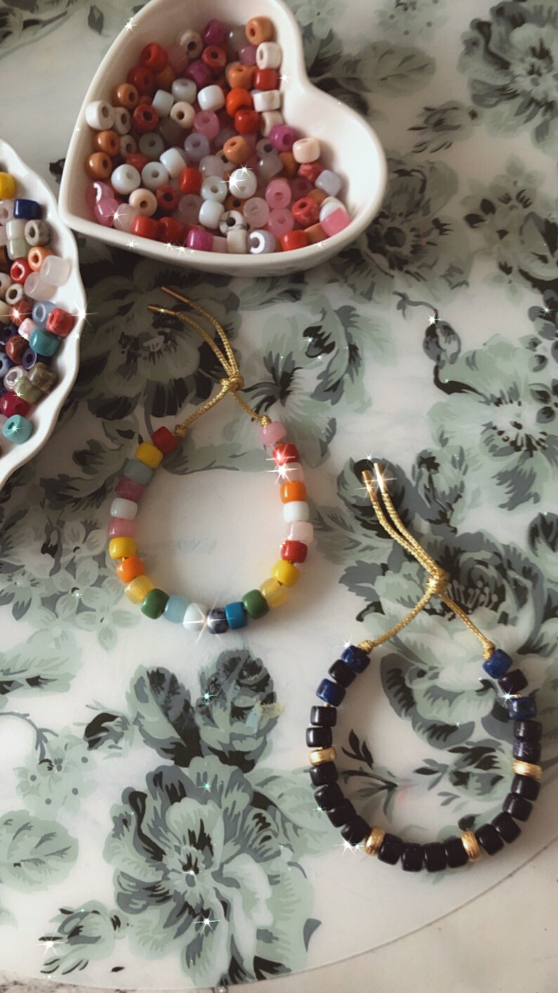 May include: Two bracelets made with colorful beads. One bracelet is made with rainbow colored beads and the other is made with black and blue beads.