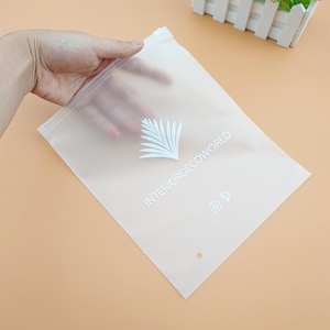 May include: A clear plastic resealable bag with a white logo that says "INTERIORDECOWORLD" and a white palm tree design. The bag has a small hole at the top and a white Instagram and Pinterest icon.