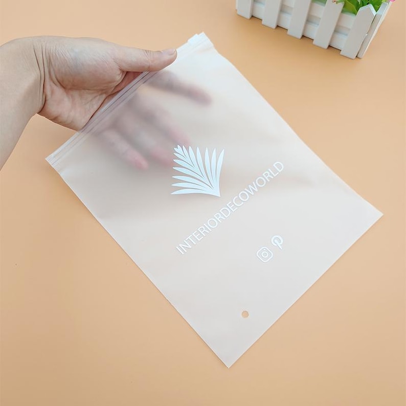 May include: A clear plastic resealable bag with a white logo that says "INTERIORDECOWORLD" and a white palm tree design. The bag has a small hole at the top and a white Instagram and Pinterest icon.
